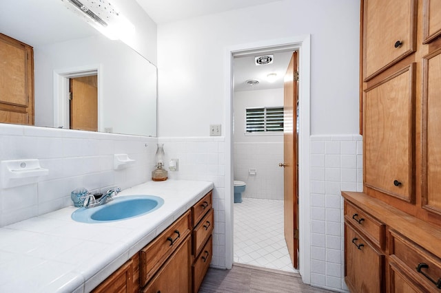 bathroom with vanity, toilet, and tile walls