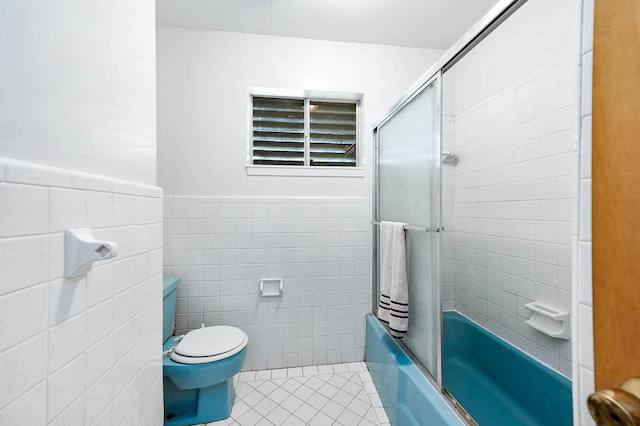 bathroom featuring tile walls, bath / shower combo with glass door, tile patterned floors, and toilet