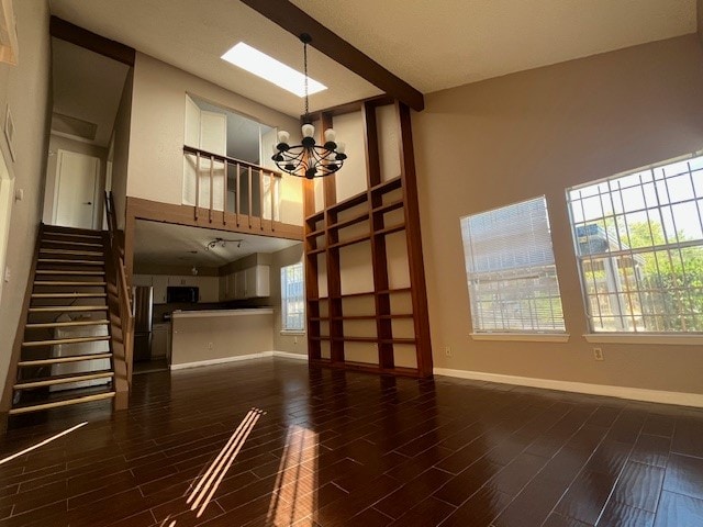 unfurnished living room featuring a chandelier, a towering ceiling, and dark hardwood / wood-style flooring