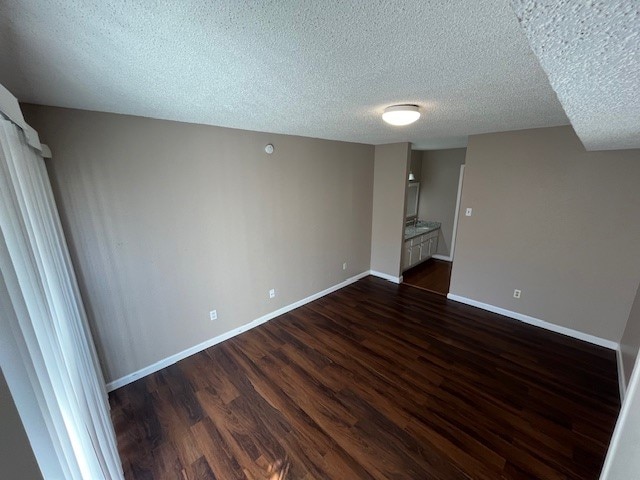 unfurnished bedroom with a textured ceiling and dark hardwood / wood-style floors