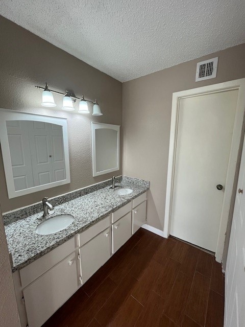 bathroom with vanity, a textured ceiling, and hardwood / wood-style floors