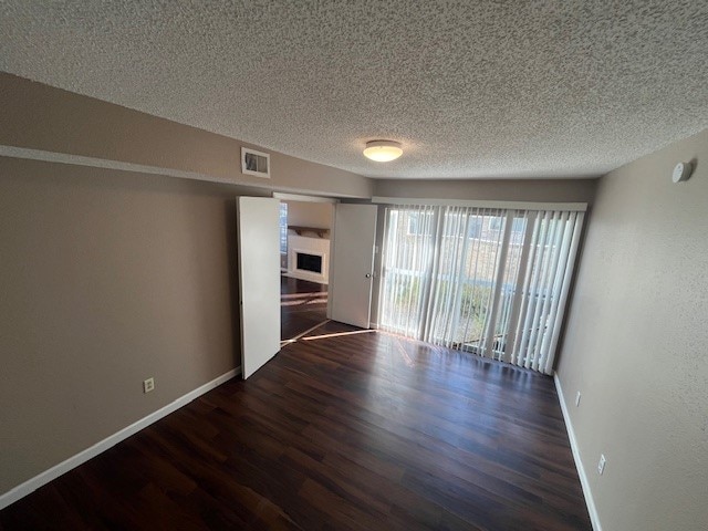 unfurnished room featuring a textured ceiling and dark wood-type flooring