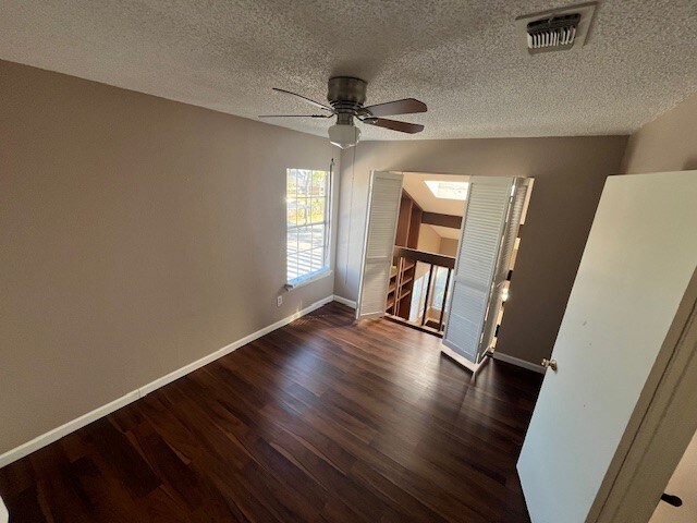 unfurnished room with a textured ceiling, ceiling fan, and dark hardwood / wood-style flooring