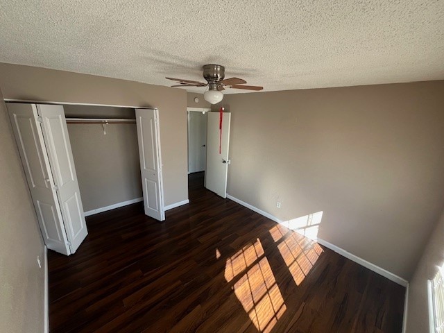 unfurnished bedroom with dark hardwood / wood-style flooring, a textured ceiling, a closet, and ceiling fan