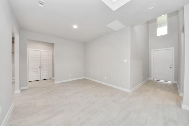 empty room with light hardwood / wood-style flooring and a skylight