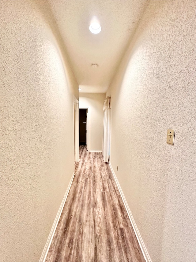 hall featuring light hardwood / wood-style floors and a textured ceiling