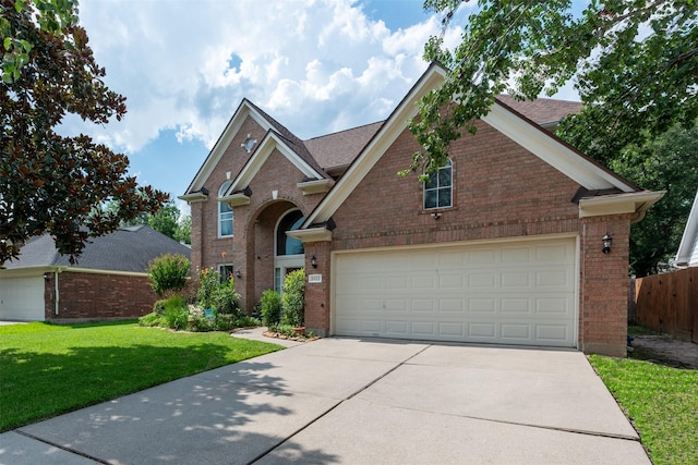 traditional-style house featuring a front lawn, driveway, a garage, and brick siding