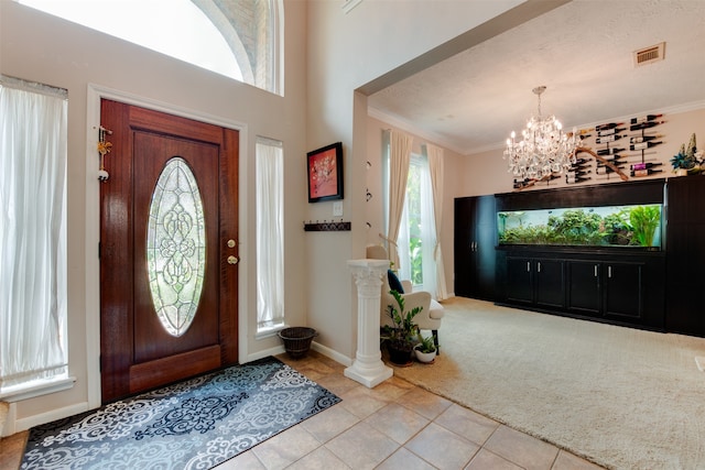 tiled foyer featuring crown molding, a textured ceiling, and an inviting chandelier