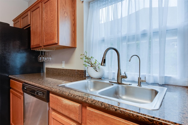 kitchen with a sink, dark countertops, dishwasher, and brown cabinetry