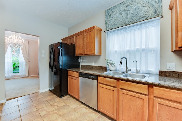 kitchen featuring stainless steel dishwasher, light colored carpet, freestanding refrigerator, a sink, and a notable chandelier