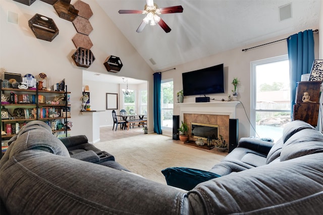 carpeted living room with a healthy amount of sunlight, high vaulted ceiling, visible vents, and ceiling fan with notable chandelier