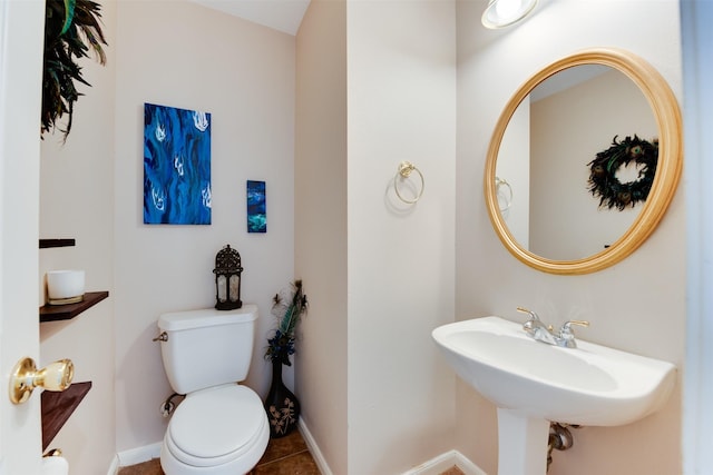 half bathroom with toilet, a sink, tile patterned floors, and baseboards