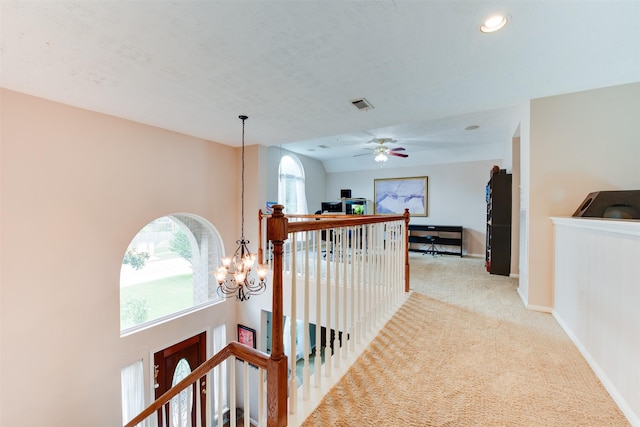corridor featuring an inviting chandelier, an upstairs landing, visible vents, baseboards, and light colored carpet