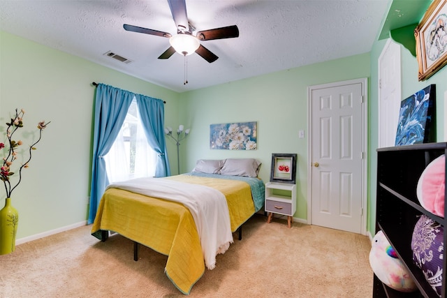 carpeted bedroom with a textured ceiling, visible vents, a ceiling fan, and baseboards
