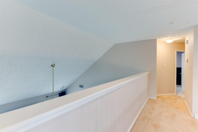 corridor featuring visible vents, vaulted ceiling, carpet floors, and baseboards