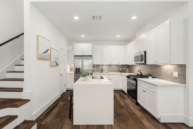 kitchen with appliances with stainless steel finishes, sink, a center island with sink, and dark hardwood / wood-style floors