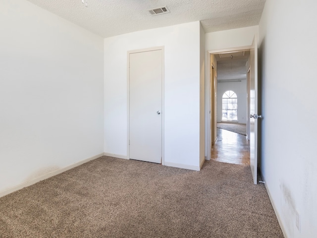 unfurnished bedroom featuring carpet, a textured ceiling, and a closet