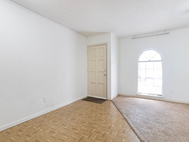 empty room featuring light parquet floors, a textured ceiling, and wooden walls