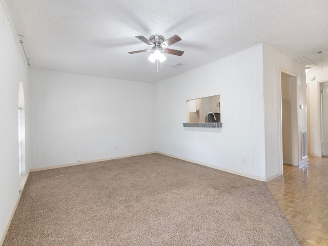 empty room with sink, ceiling fan, a textured ceiling, and light parquet floors