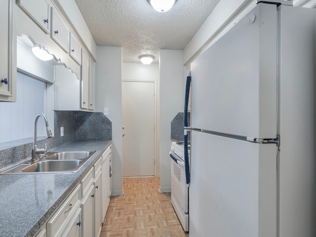 kitchen featuring sink, light parquet floors, white cabinetry, a textured ceiling, and white appliances