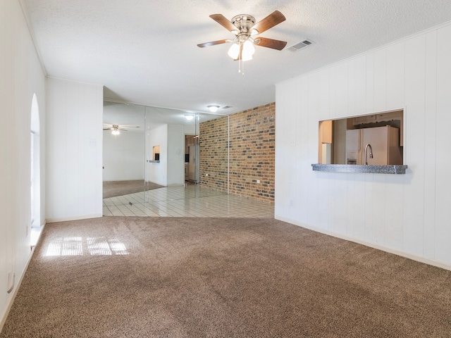 carpeted spare room featuring wood walls, a textured ceiling, and ceiling fan