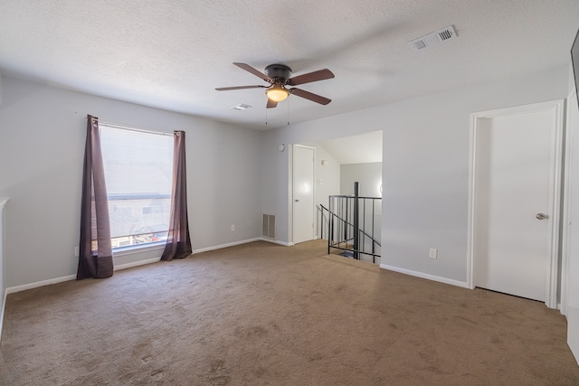 carpeted spare room featuring a textured ceiling and ceiling fan