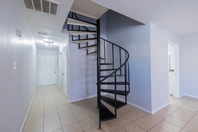 stairs featuring a textured ceiling and tile patterned flooring