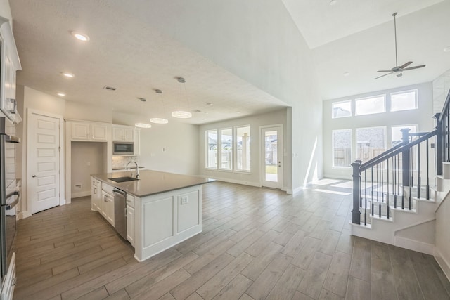 kitchen featuring light hardwood / wood-style flooring, an island with sink, stainless steel appliances, sink, and white cabinetry