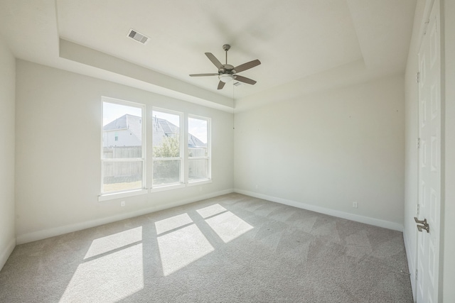 carpeted spare room featuring ceiling fan and a tray ceiling