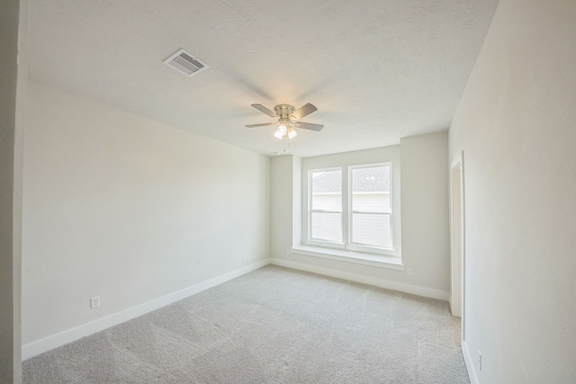 spare room featuring ceiling fan, a textured ceiling, and light colored carpet