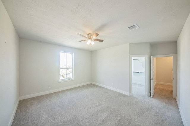 carpeted spare room with a textured ceiling and ceiling fan