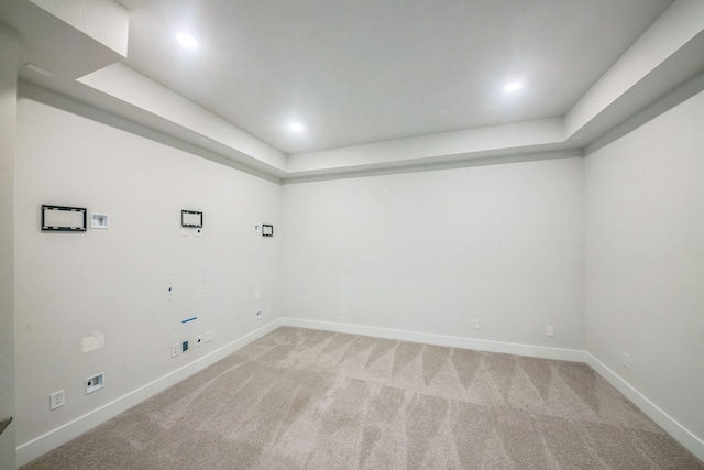 unfurnished room with light colored carpet and a raised ceiling