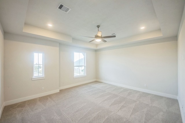 carpeted empty room featuring a tray ceiling and ceiling fan