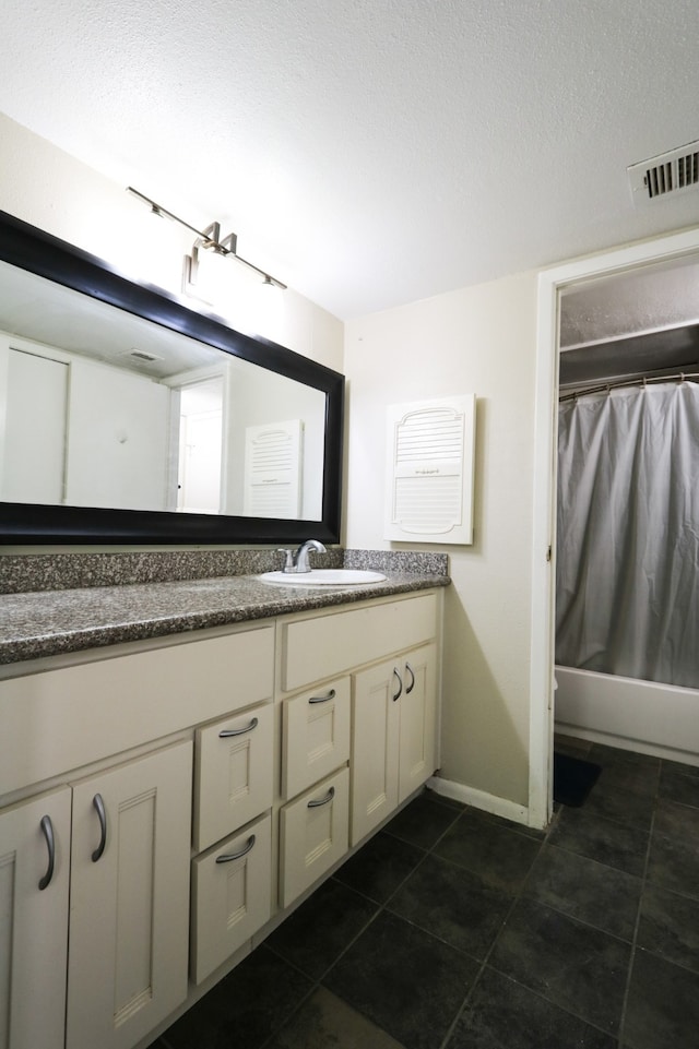 bathroom with vanity, shower / tub combo with curtain, tile patterned floors, and a textured ceiling