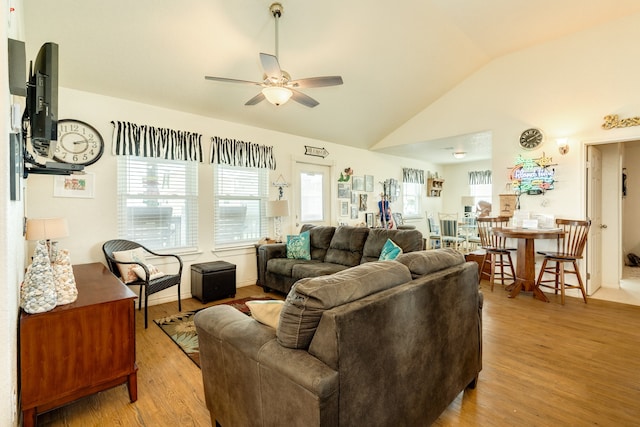 living room with light hardwood / wood-style floors, a healthy amount of sunlight, and vaulted ceiling