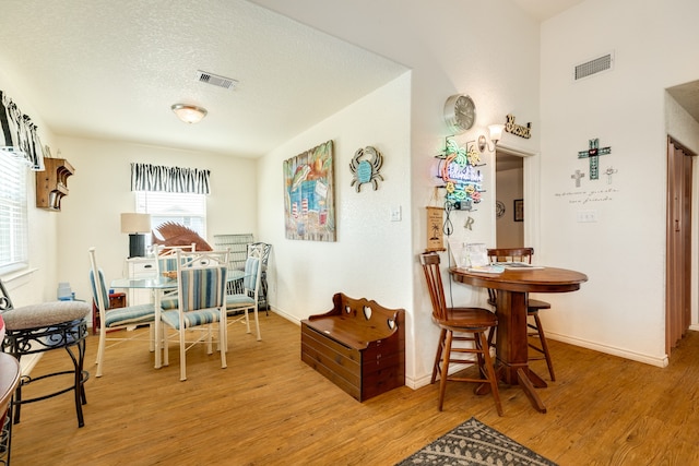 dining room with light hardwood / wood-style flooring and a textured ceiling