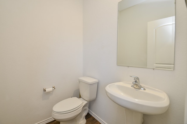 bathroom with toilet, wood-type flooring, and sink