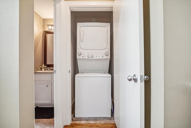 clothes washing area featuring light hardwood / wood-style floors, stacked washer / dryer, and sink