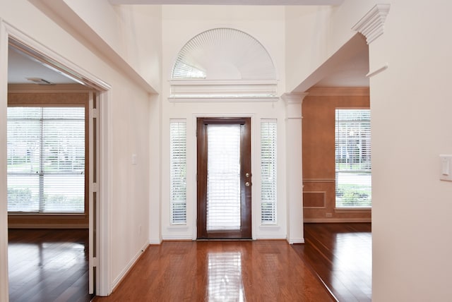 foyer with ornate columns, a healthy amount of sunlight, and dark hardwood / wood-style flooring