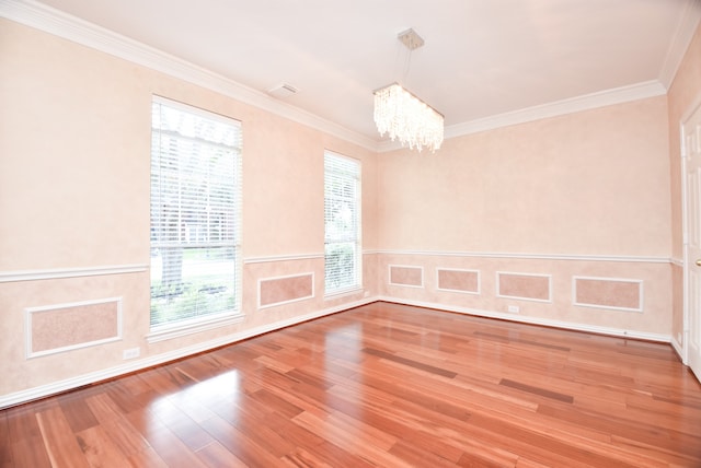 empty room with a notable chandelier, hardwood / wood-style flooring, and ornamental molding