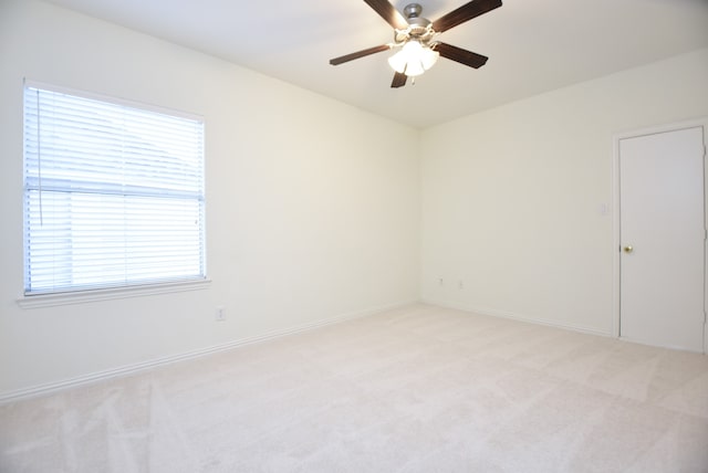 carpeted spare room featuring a healthy amount of sunlight and ceiling fan