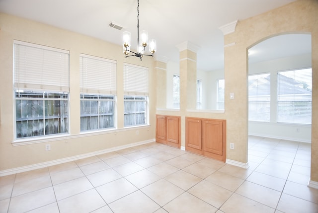 unfurnished dining area featuring a chandelier, decorative columns, and light tile patterned floors