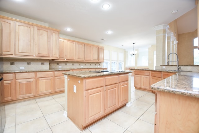 kitchen with tasteful backsplash, light brown cabinetry, a kitchen island, and hanging light fixtures