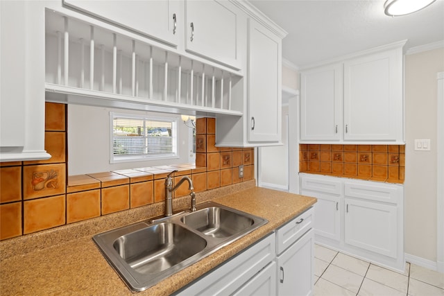 kitchen featuring decorative backsplash, white cabinetry, light tile patterned flooring, crown molding, and sink