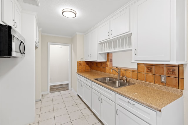 kitchen featuring backsplash, sink, crown molding, light tile patterned floors, and white cabinetry