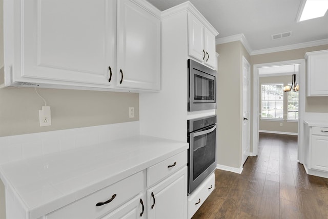 kitchen featuring crown molding, appliances with stainless steel finishes, dark hardwood / wood-style flooring, and white cabinets