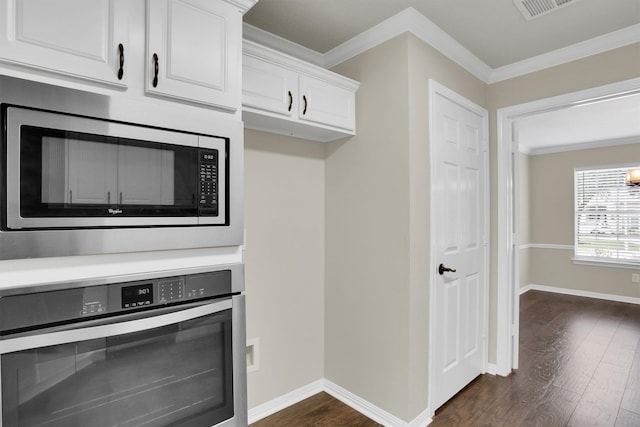 kitchen featuring dark wood-type flooring, appliances with stainless steel finishes, crown molding, and white cabinetry