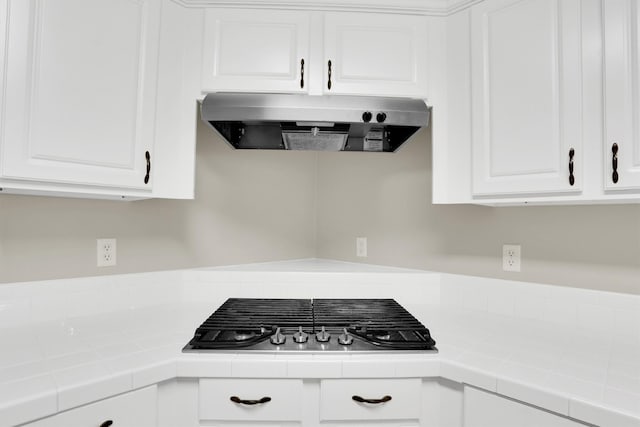 kitchen featuring tile countertops, white cabinets, exhaust hood, and black gas stovetop