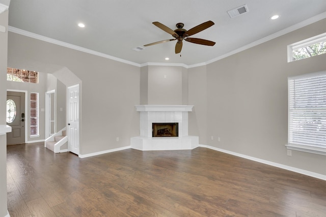 unfurnished living room with ornamental molding, dark wood-type flooring, a tiled fireplace, and ceiling fan