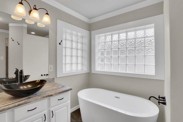 bathroom featuring a wealth of natural light, vanity, ornamental molding, and a bathing tub